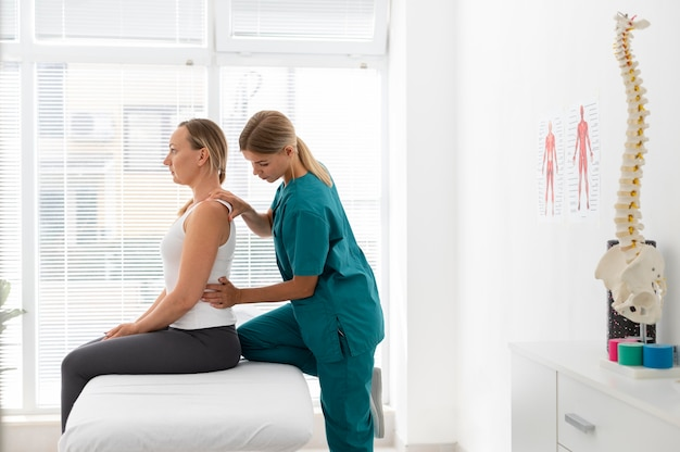 a chiropractor with her hands on a woman’s shoulders and waist